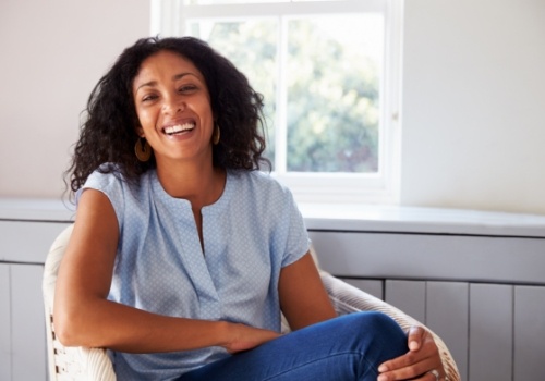 Smiling woman in light blue blouse sitting in white wicker chair