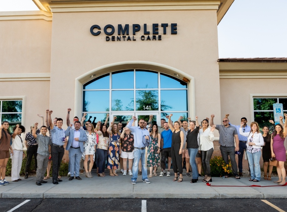 Group of people fist pumping after ribbon cutting at Complete Dental Care Paradise Valley