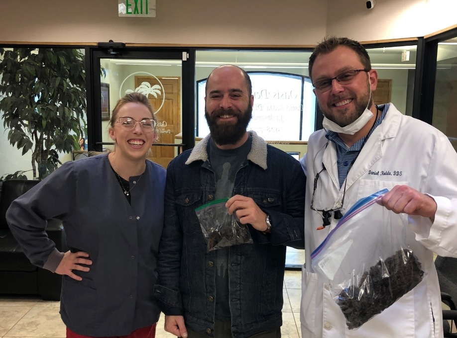 Doctor Rodda and another man holding plastic bags with a woman in scrubs at community event