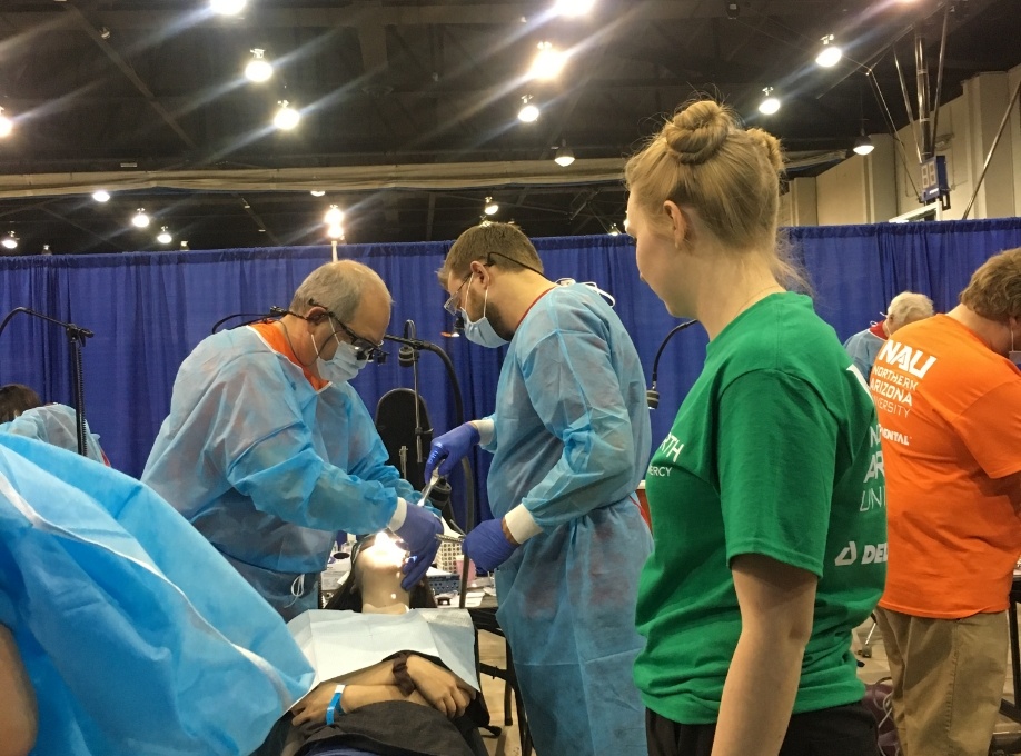 Doctor Rodda and another dentist treating a patient at community event