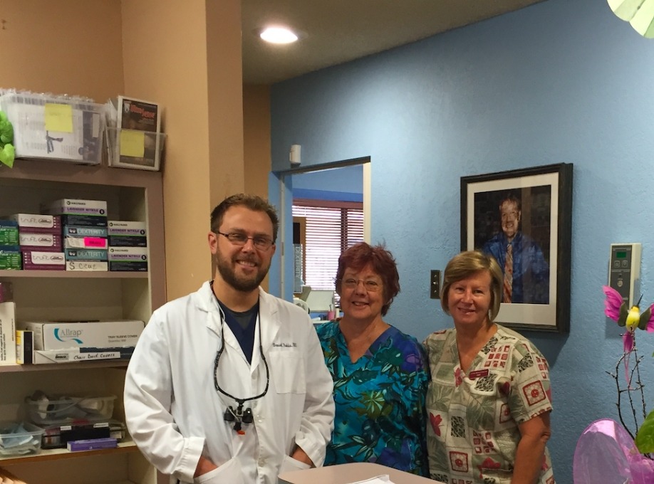 Doctor Rodda smiling with two older women in scrubs