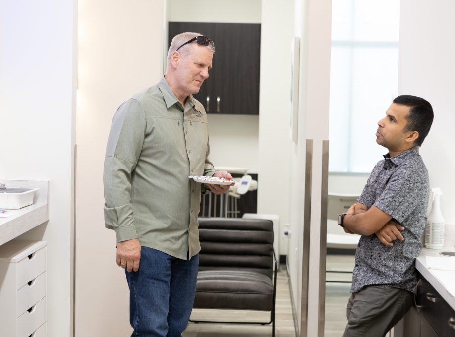 Two men talking in dental office with one holding a plate of food