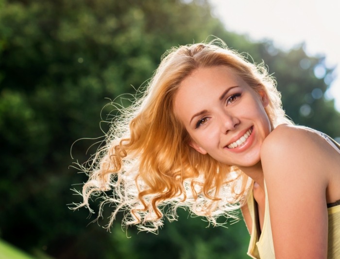 Woman with curly blonde hair grinning outdoors