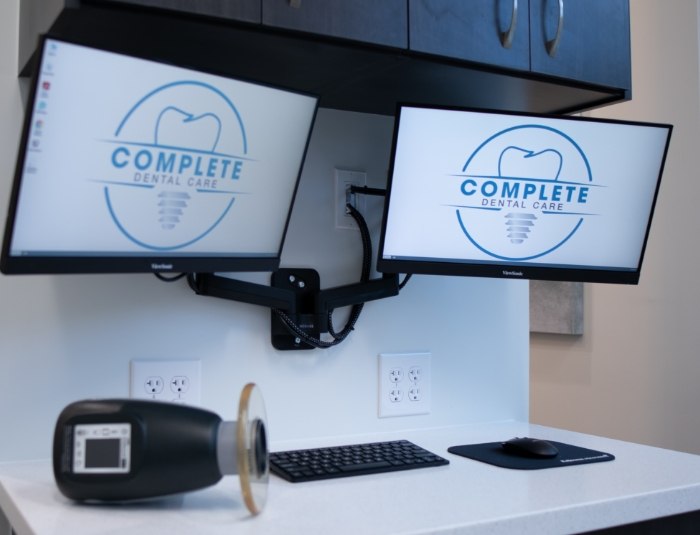 Two computer monitors showing the logo for Complete Dental Care Paradise Valley