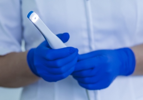 Two gloved hands holding an intraoral camera