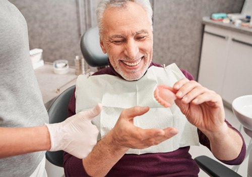 A dentist showing dentures to a patient