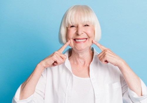 An older woman pointing out her beautiful smile