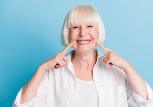 An older woman pointing out her beautiful smile