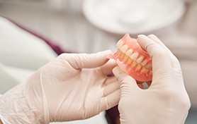 White gloved hands holding a set of dentures