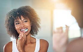 Woman smiling while brushing his teeth
