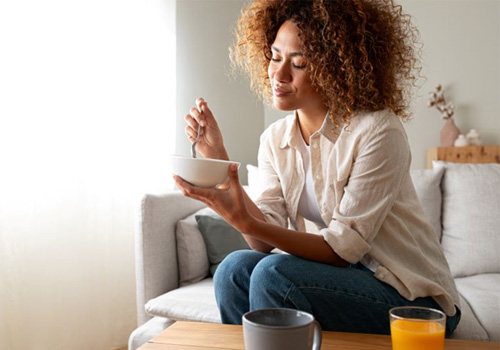 Woman sitting on sofa, eating from a bowl
