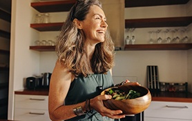 a woman smiling while holding a bowl of healthy food