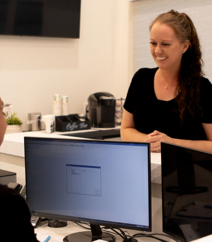 Woman smiling at dental team member at front desk of Phoenix dental office