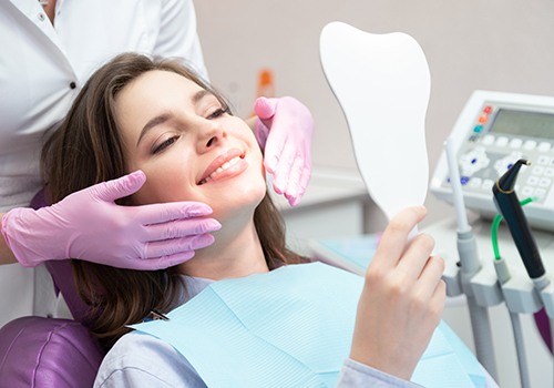 a patient admiring her cosmetic dental results 