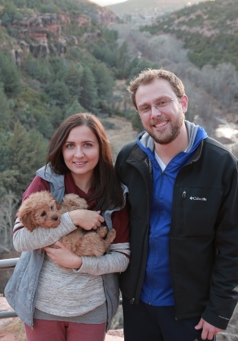 Doctor Rodda and his partner on a mountaintop holding a small puppy