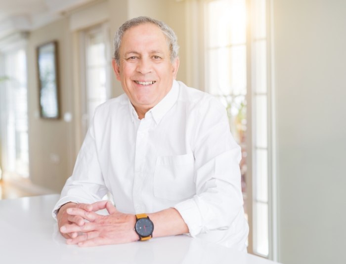 Senior man in white collared shirt smiling after replacing missing teeth in Phoenix