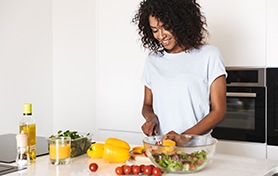 Woman smiling while chopping vegetables in kitchen