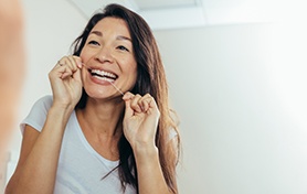 Woman smiling while flossing her teeth