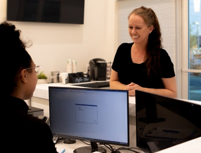 Dental patient talking to dental team member at reception desk