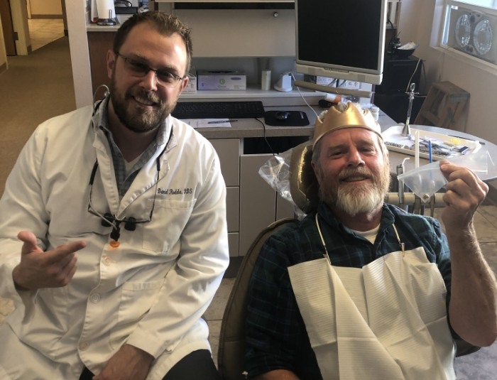 Doctor Rodda with dental patient holding old dental work in plastic bag