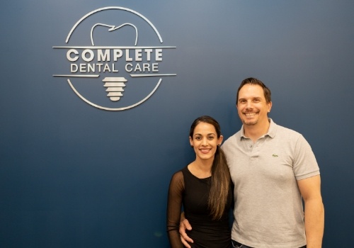 Smiling man and woman in front of Complete Dental Care Paradise Valley sign on wall