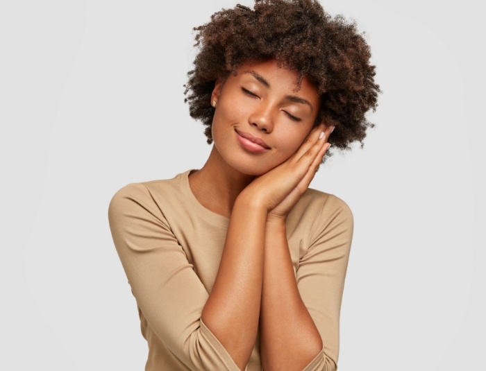 Woman forming a pillow shape with her hands and pretending to sleep